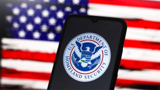 Phone screen displaying US Department of Homeland Security logo in front of a US flag