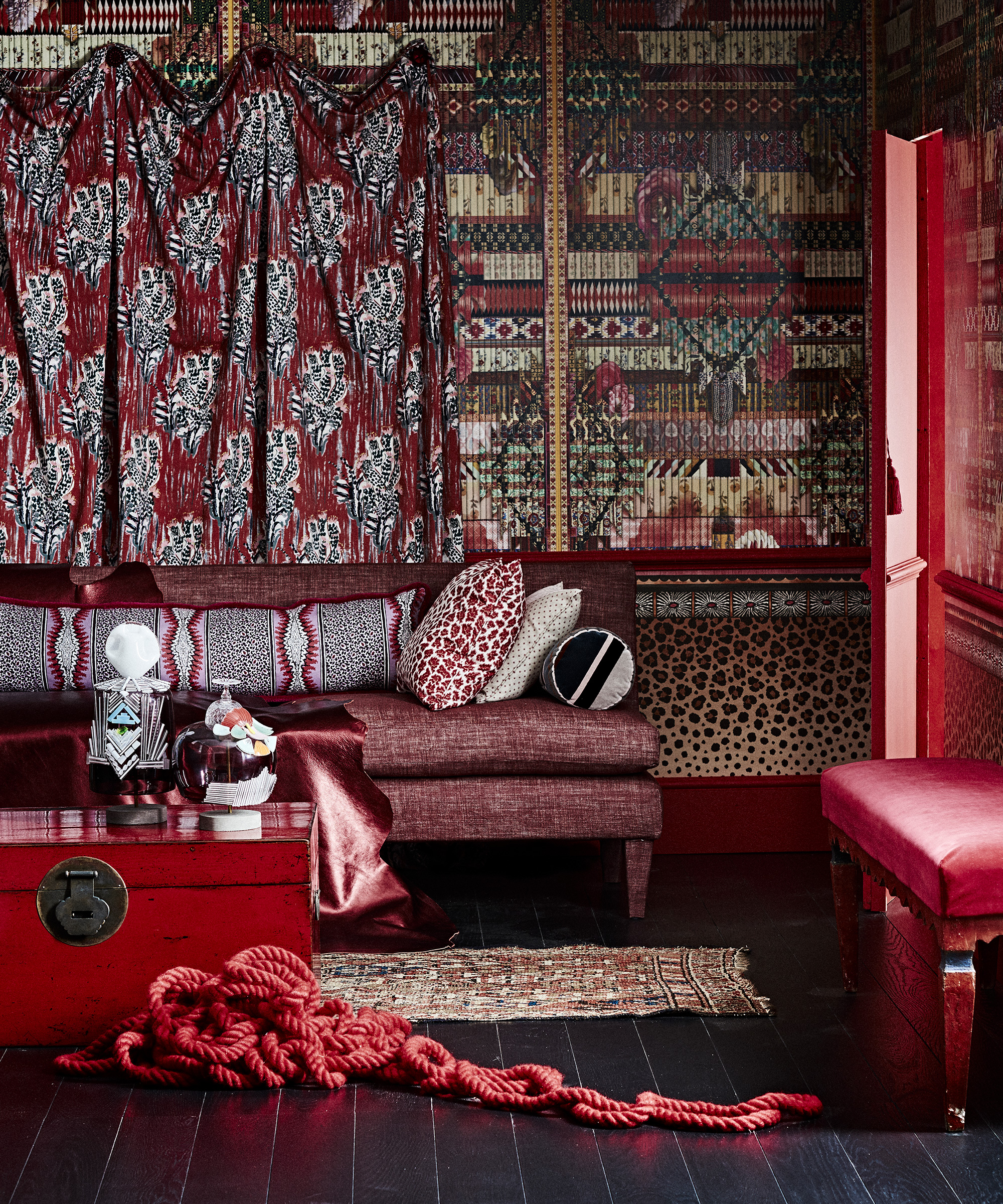 An example of wallpaper trends showing a luxurious red room with animal print soft furnishings and bold wallpaper