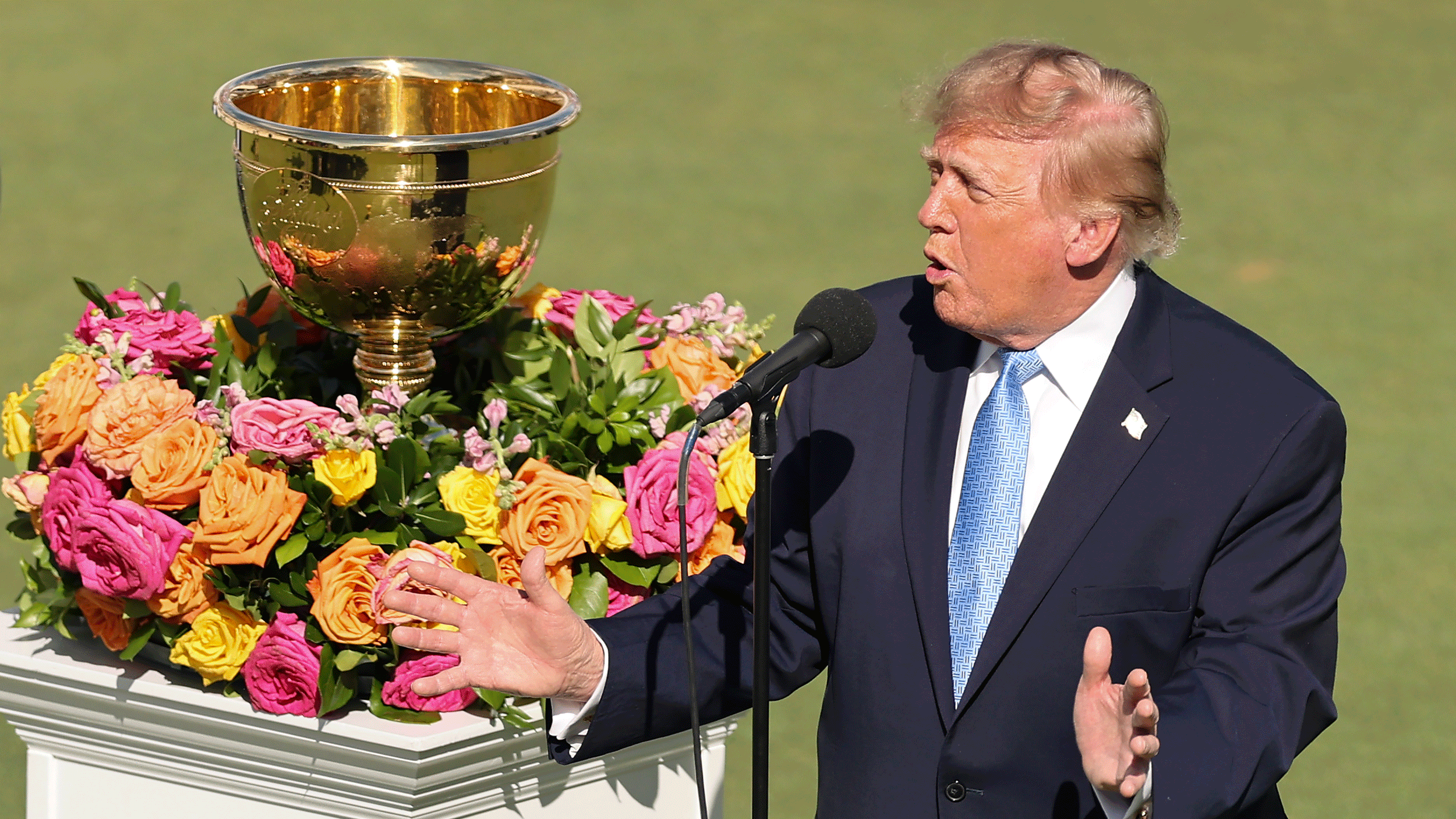 Donald Trump speaks on the final day of the 2026 Presidents Cup with the trophy in the background