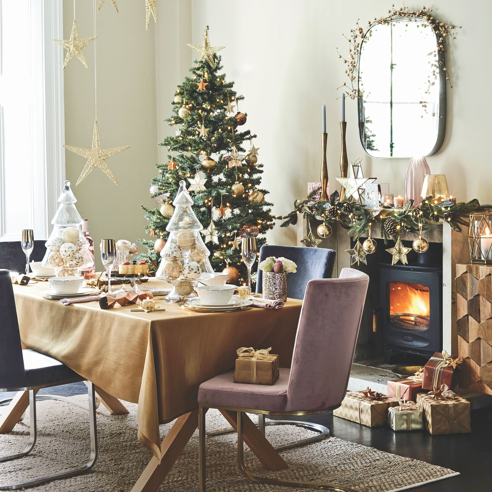 Festive dining room with gold decorations on the tree, on the dining room table and above a mantlepiece