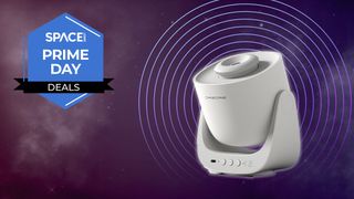 A projector is mounted on a wide-based stand and connected at either side, is surrounded by a faint white glow on a purple starry background with the space.com logo in the top left corner.