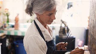 woman with grey hair painting a picture