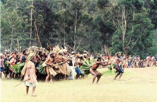Clan of the deceased Enga people performs a traditional mock attack upon arrival to receive compensation.