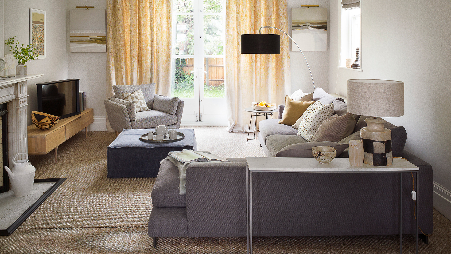 neutral living room with large grey corner sofa, hessian flooring, lined curtains and lamps