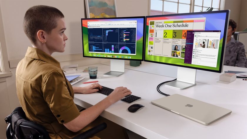 A person uses a MacBook Air connected to two external Apple Studio Displays.