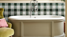a freestanding grey bath with green and white gingham tiling behind it