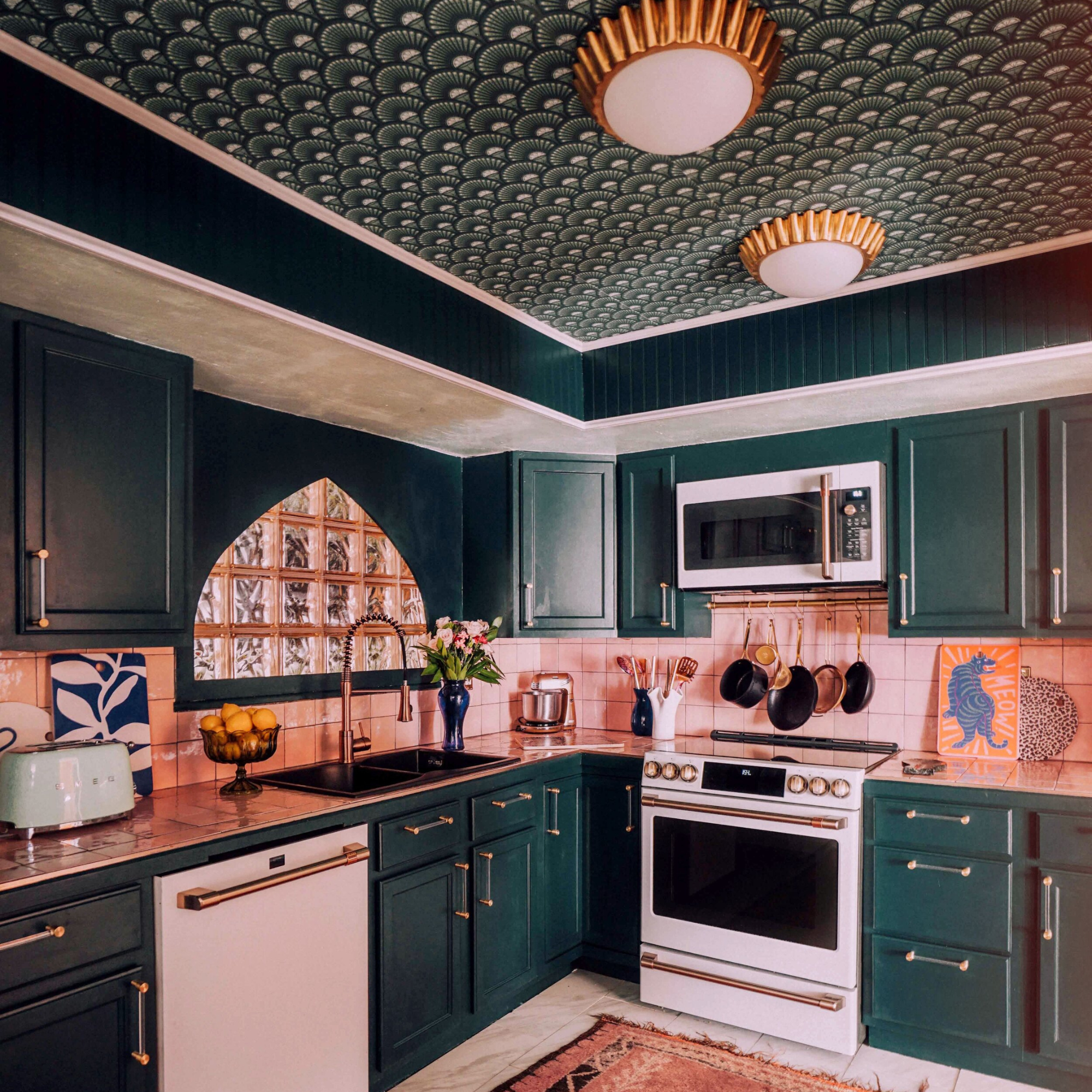 a green painted kitchen with art deco style wallpaper on ceiling