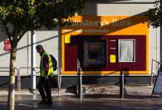 Sainsbury's employee walking past Sainsbury's Bank cash machine