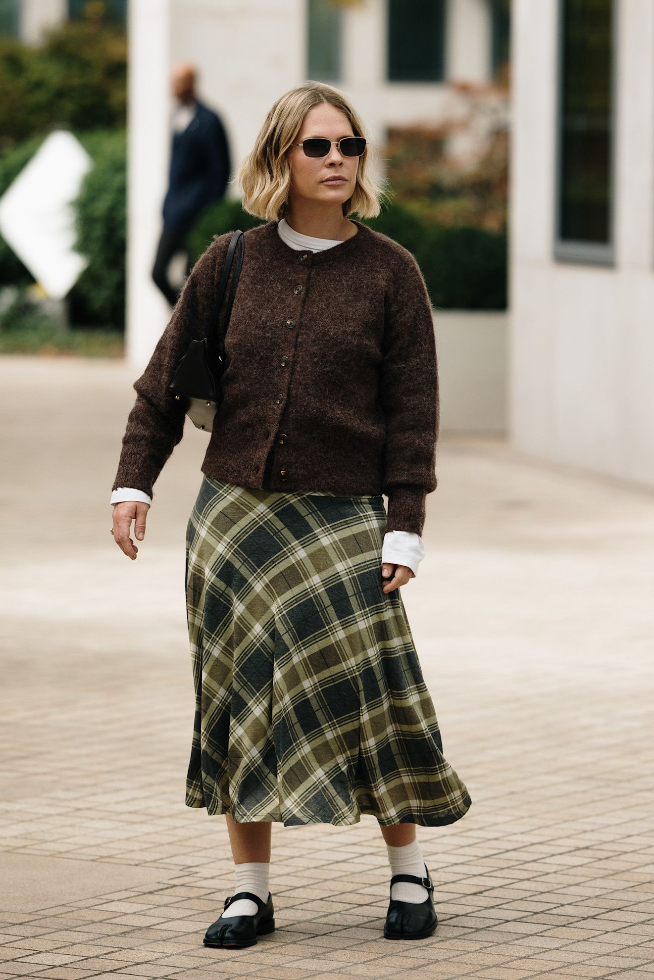 woman wearing sweater, plaid skirt, and ballet flats