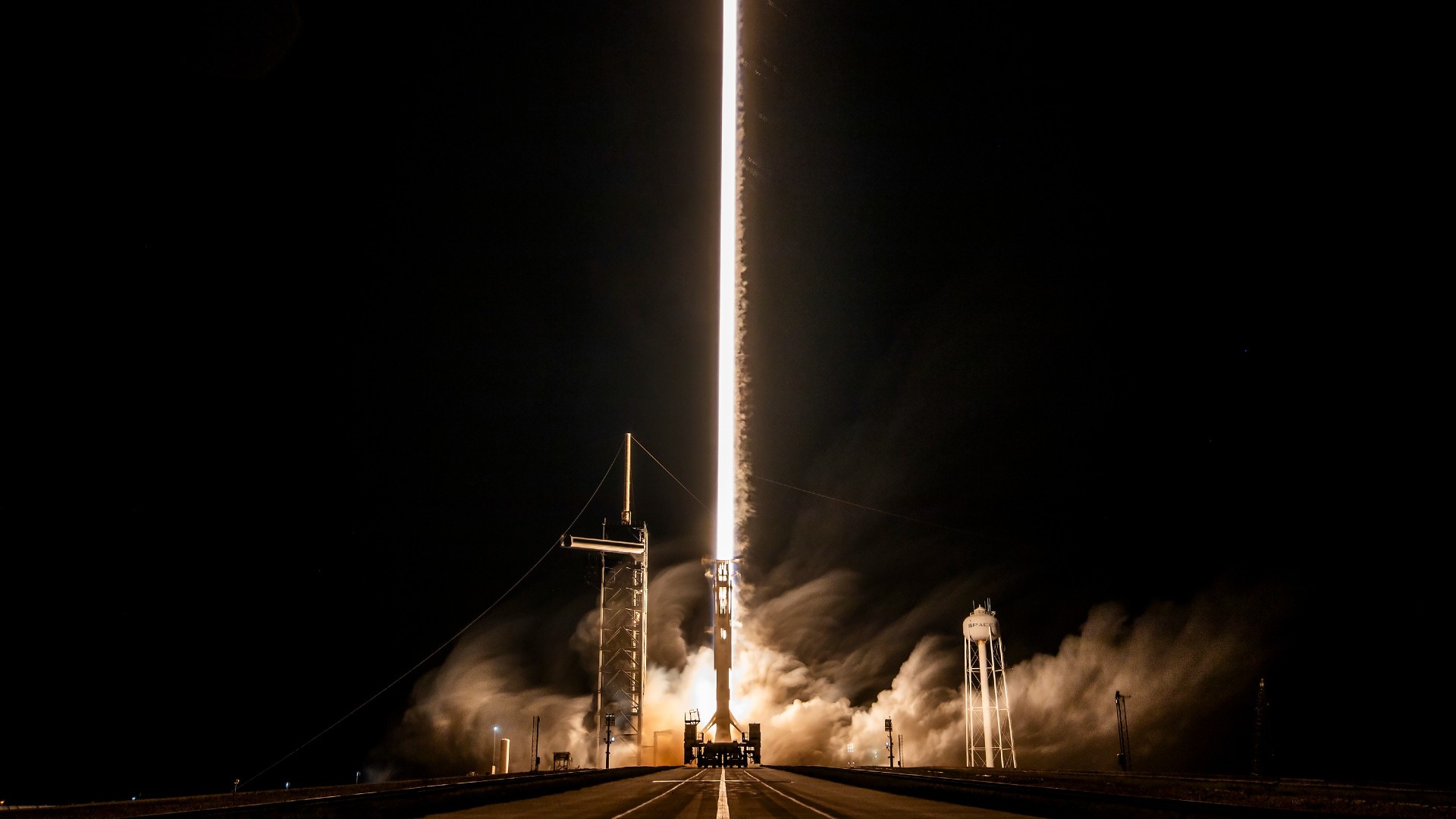 a white rocket lifts off above a plume of fire
