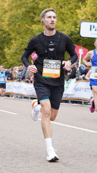 Sam Rider, a man in black running kit and white trainers, running along a road in the Royal Parks Half Marathon