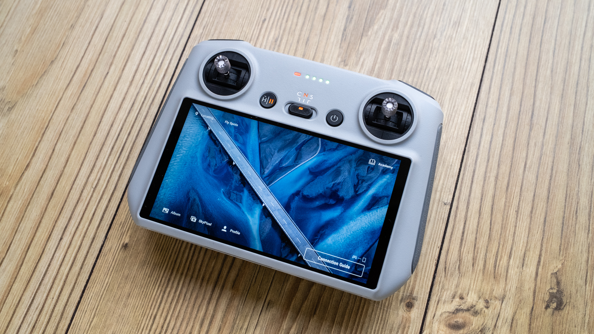 DJI Mini 3 RC-N1 controller with screen turned on, on top of a wooden table