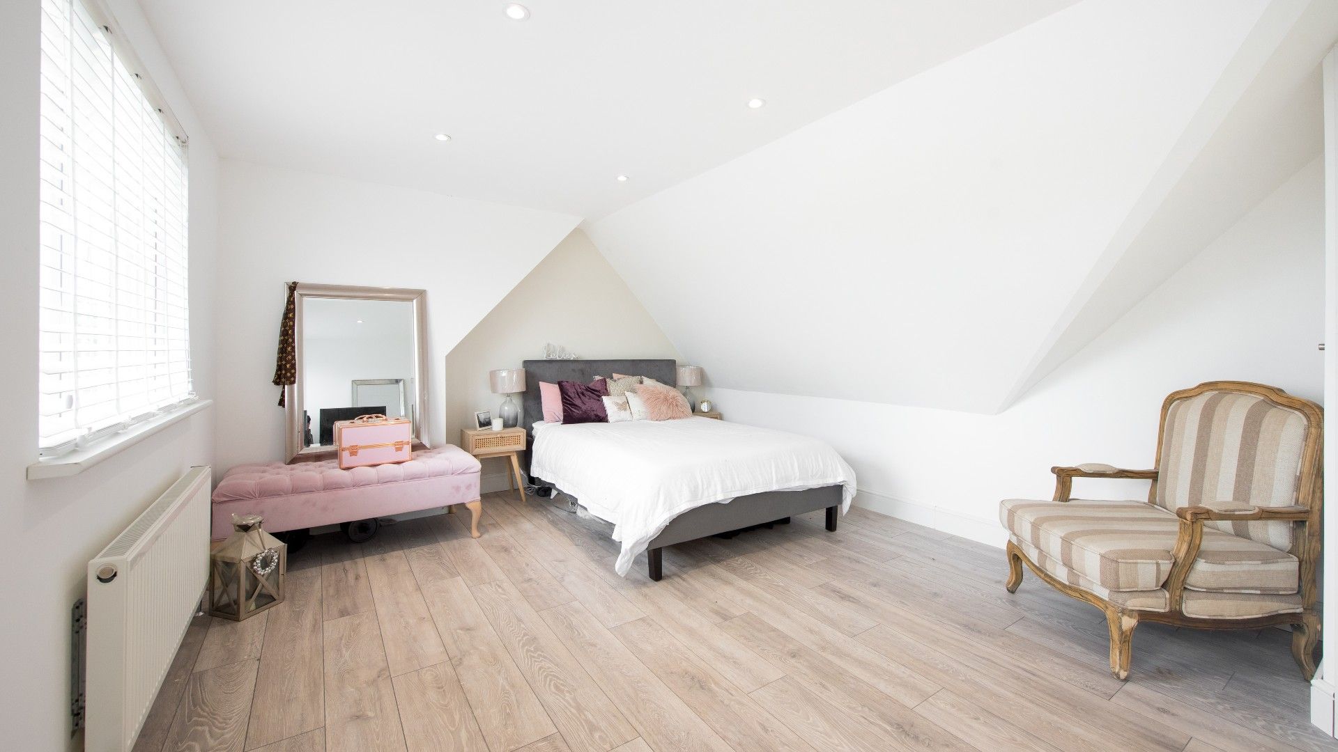 laminate flooring in a bedroom with an ottoman and an armchair