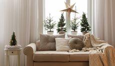 beige and white living room christmas decor focusing on the couch in front of a window with trinkets placed about