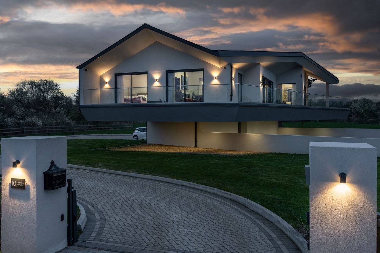 The gate which is lit wall lighting leads to the curved updward driveway
