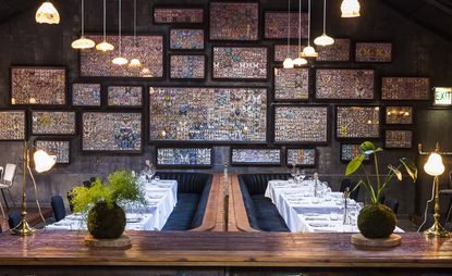 Tables set on white table cloths and blue velvet seats with framed butterflies hanging on the walls