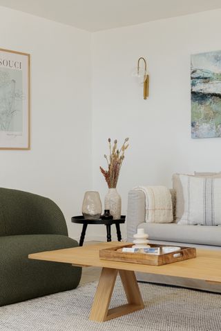 A living room with a low profile wooden coffee table, two sofas, and a gold exposed bulb sconce on the wall