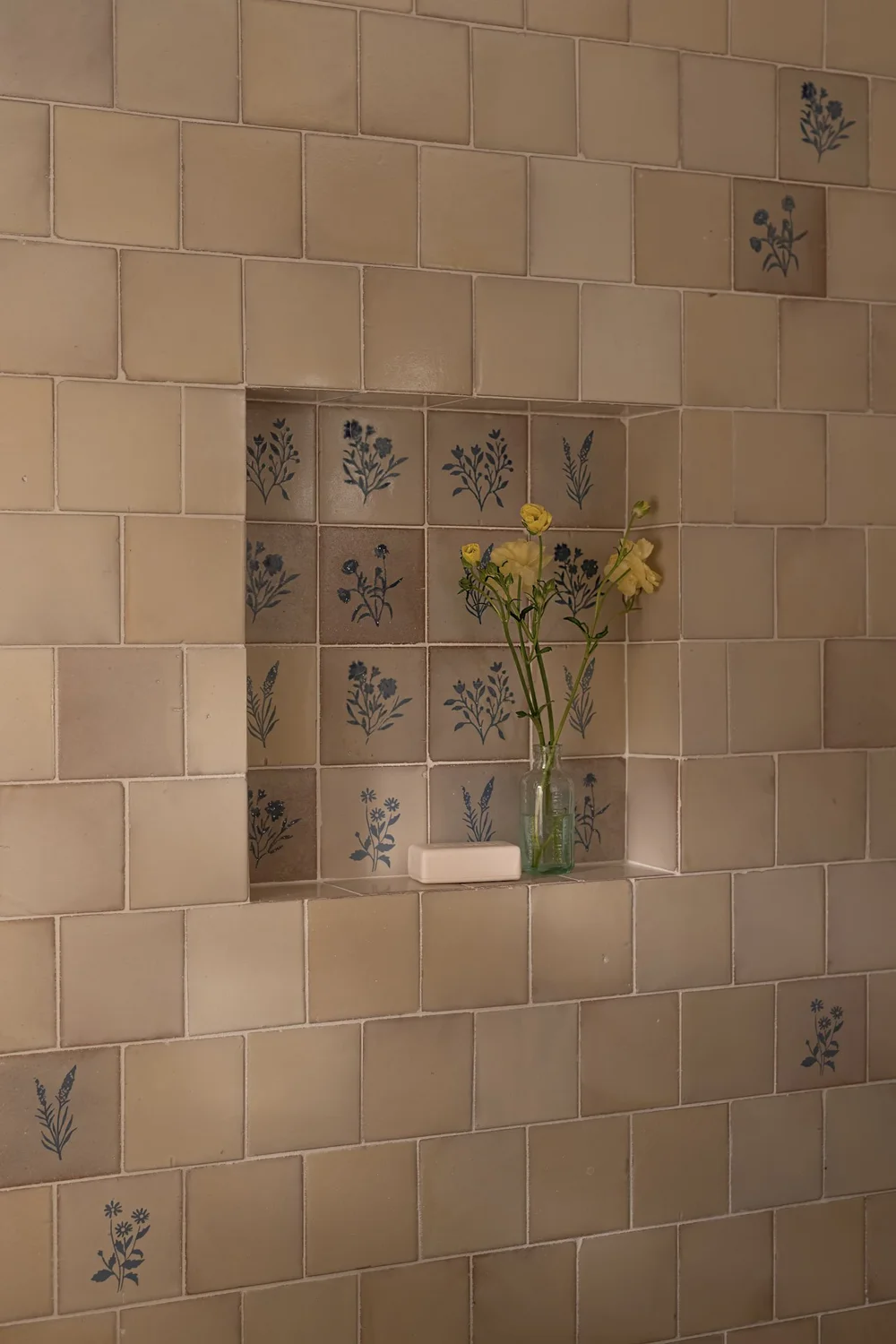A tiled shower with botanical motifs decorating some tiles