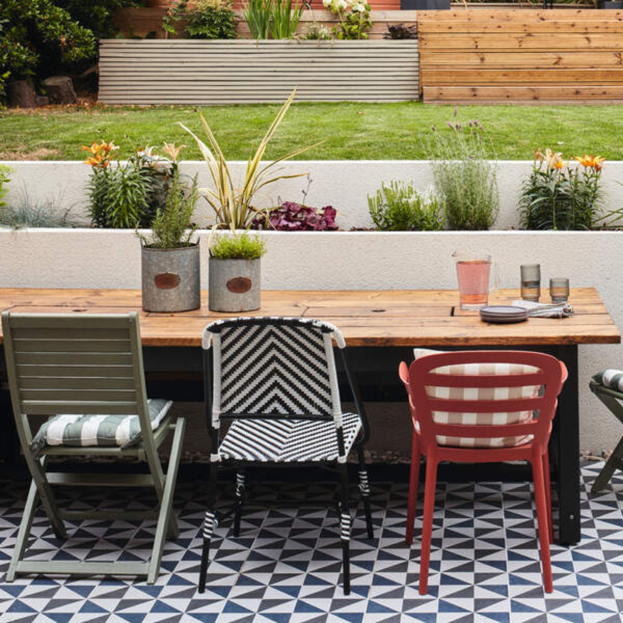 a white and black tiled seating zone, with a wooden table and bright mis-match chairs