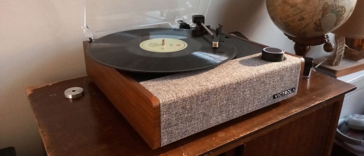 The Victrola Eastwood II turntable on a wooden surface next to a globe.