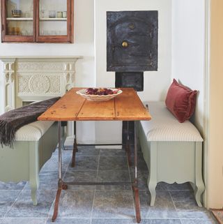 Small Suffolk cottage dining room with wooden table and painted bench seating with in-built storage