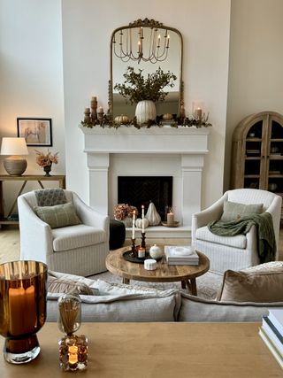 A living room with a mantel decorated with flowers and pumpkins