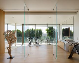 Clear glass doors leading to home gym with wood floor and two exercise bikes facing view to exterior