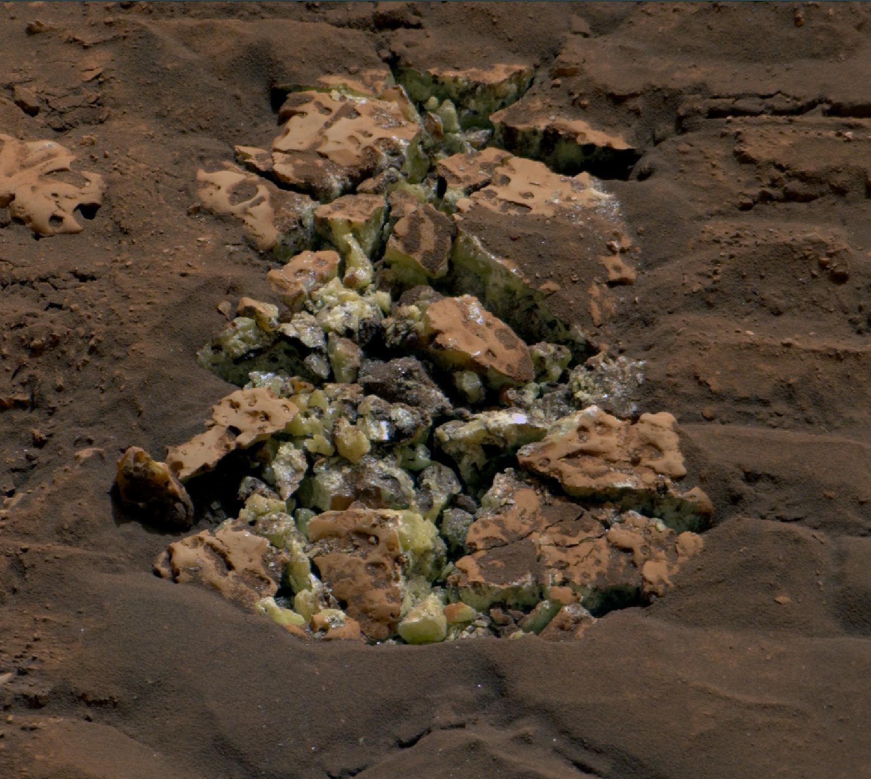 A close up of green and brown rocks in a hole in the ground.