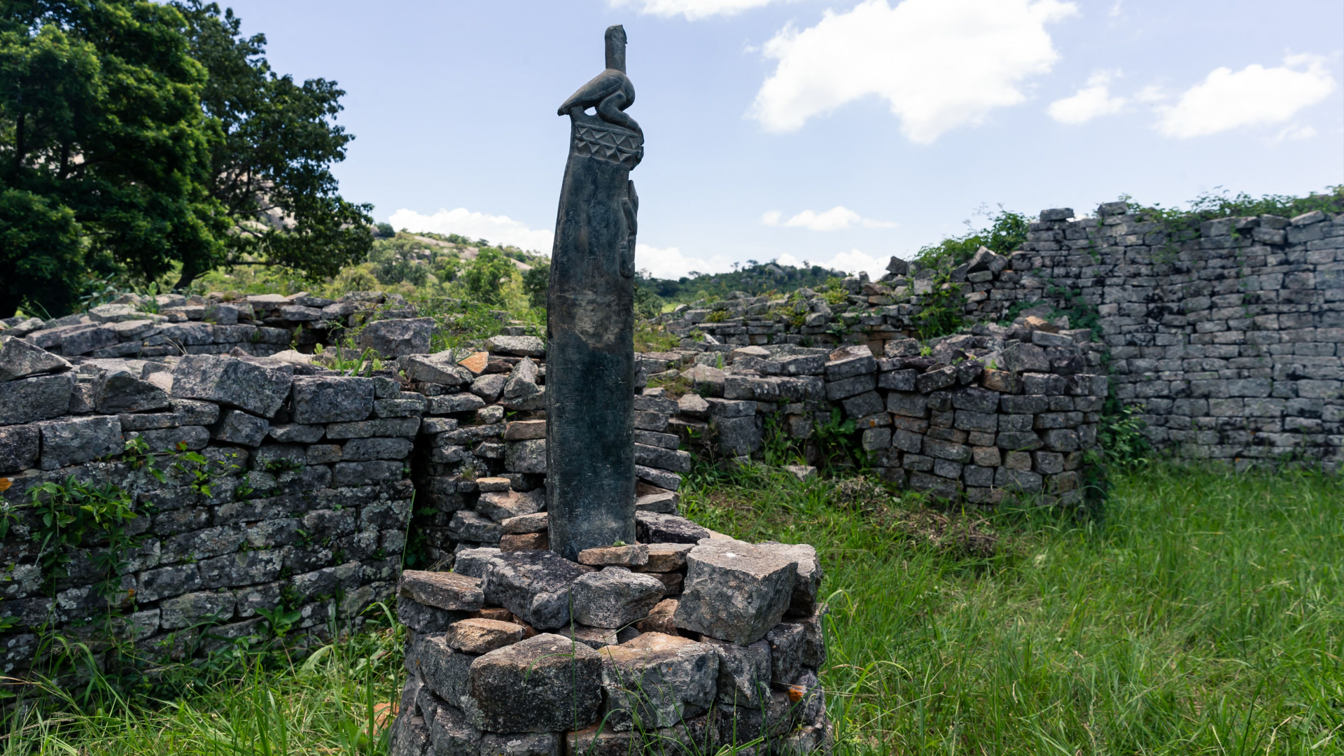 a tall soapstone carving of a bird stands in the middle of a ring of stones