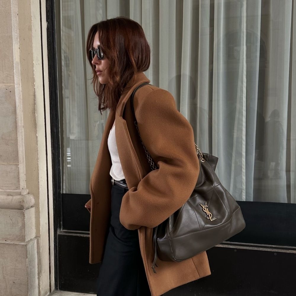 Woman wears brown wool blazer, white T-shirt, black trousers, carries Saint Laurent Jamie Shopping bag
