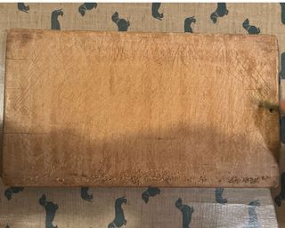 Scraping a wooden chopping board on a beige table cloth with teal dachsunds