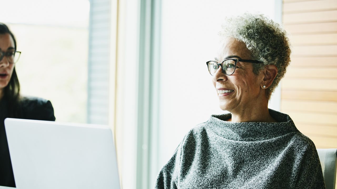 An older woman smiles while at work in an office.