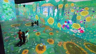 A Christie laser projector engulfs children in bright green grass, crystal-clear blue sky, and brightly colored flowers.