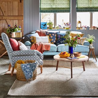 A colourful living room with a blue sofa and patterned armchair