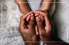 parents hands cradling newborn baby's feet