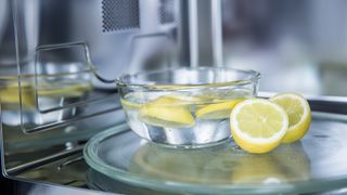 A bowl of lemons in a microwave to demonstrate a steaming kitchen cleaning hack for microwaves