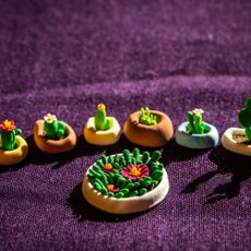 A row of tiny clay cacti in pots