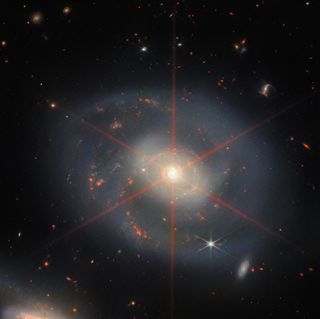 A face-on galaxy, with gray spiral arms, sprinkled with bright red patches of star formation