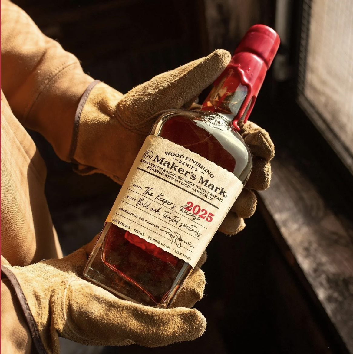 an image of the bottle of The Keeper's Release from 2025 which is being held in the gloved hands of one of the distillers
