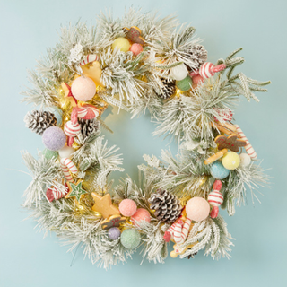 A pastel themed Christmas wreath with ornaments and pinecones