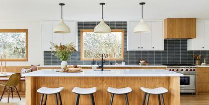 Kitchen lighting ideas with white pendants with black cables over a white oak island with marble top in a black and white kitchen