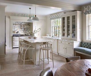 An all white kitchen with a natural stone tile floor