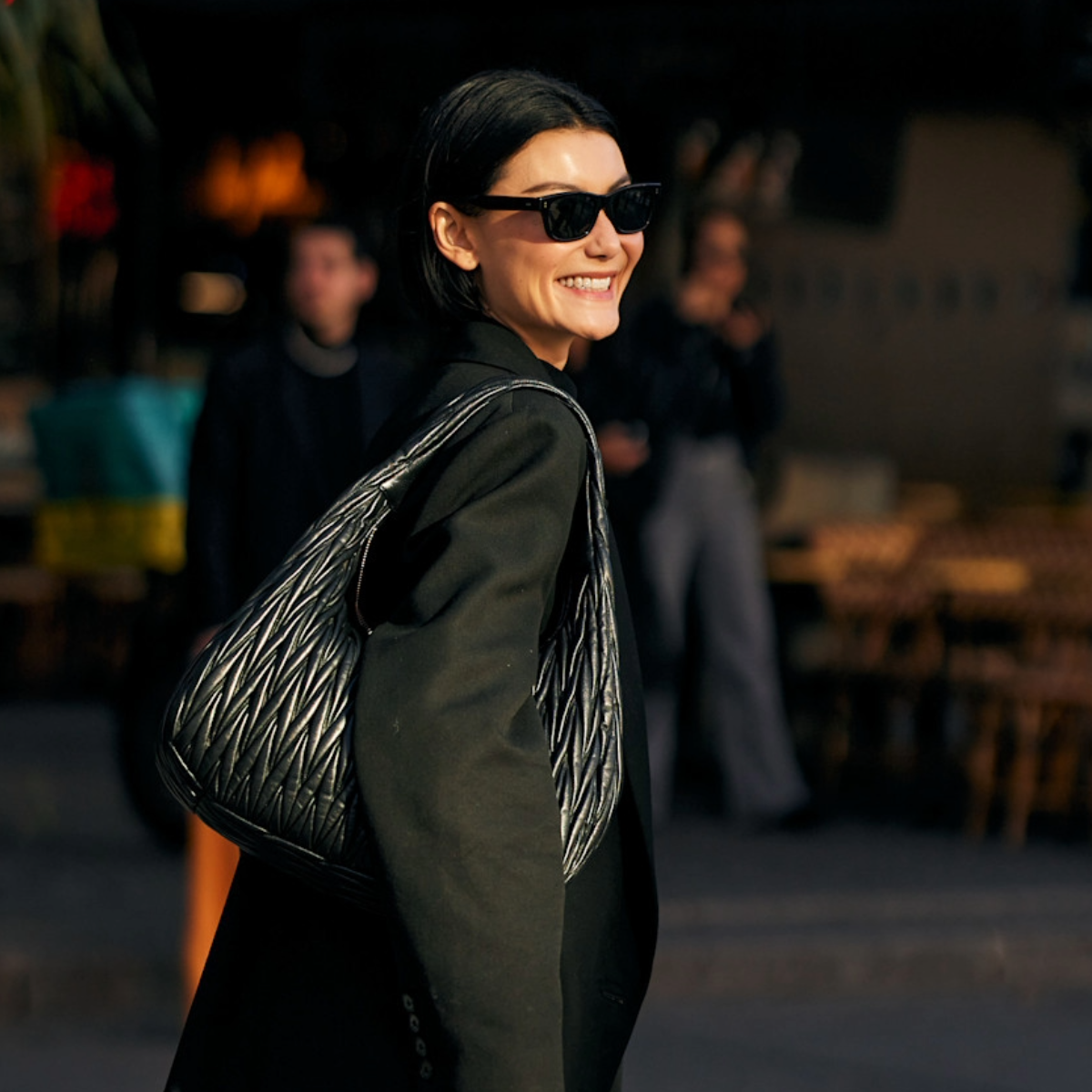 woman carrying a black tote bag and black sunglasses in Paris