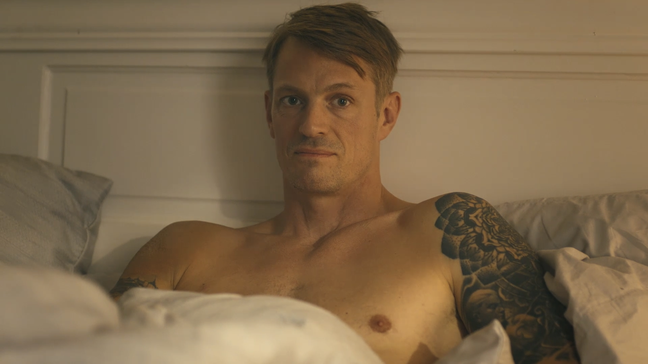 Joel Kinnaman sitting up in a bed in Peacemaker Season 2
