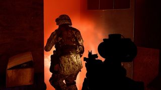 Two marines move through a dark room in orange lighting