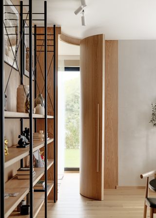 A curved wood door leading from the living room to the bedroom.