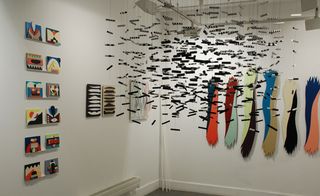 Black and White Swarm, 2009. Many microphones hanging from the roof in front of walls with paintings on them.