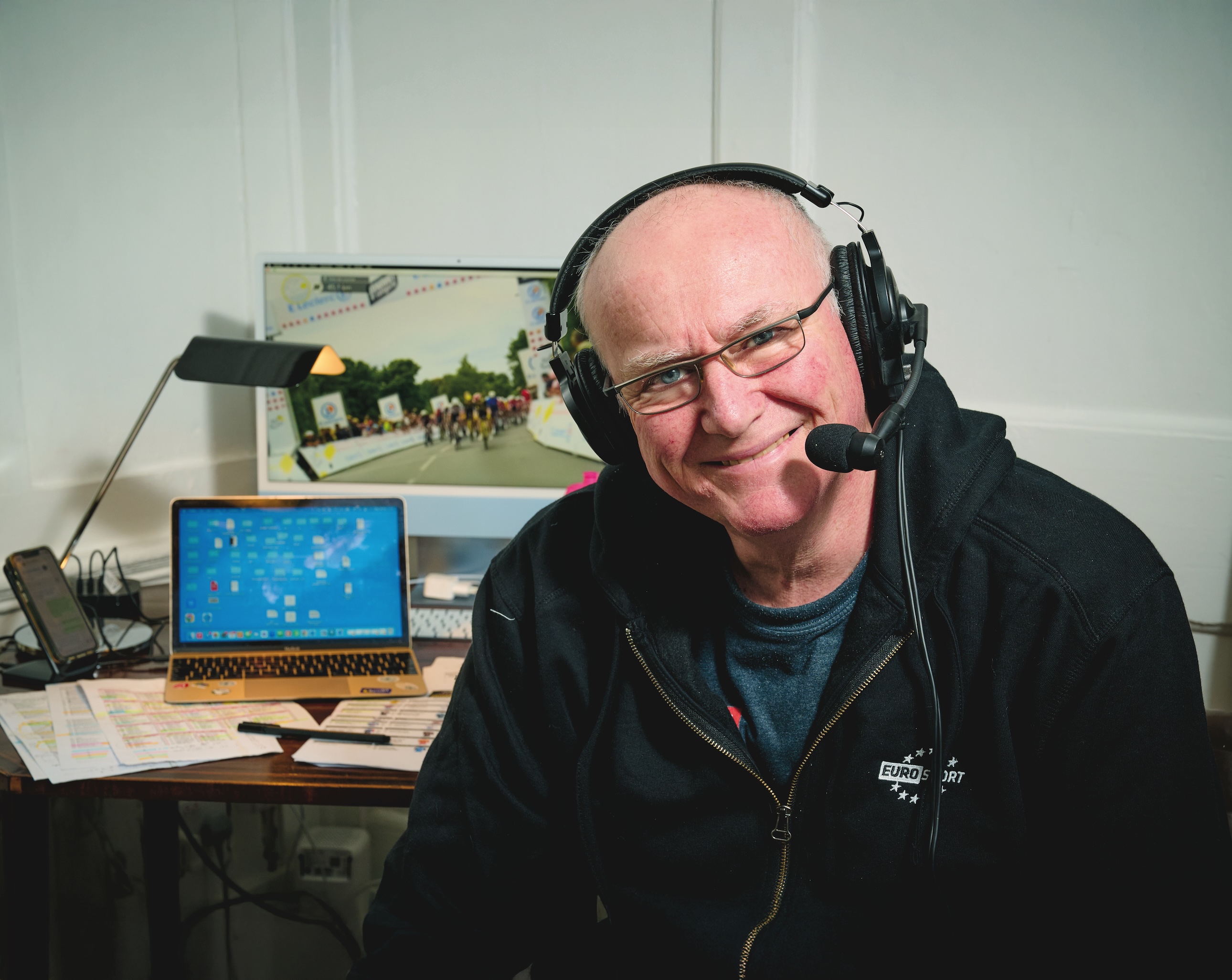 Carlton Kirby sitting at his commentating booth wearing headphones and mic set 