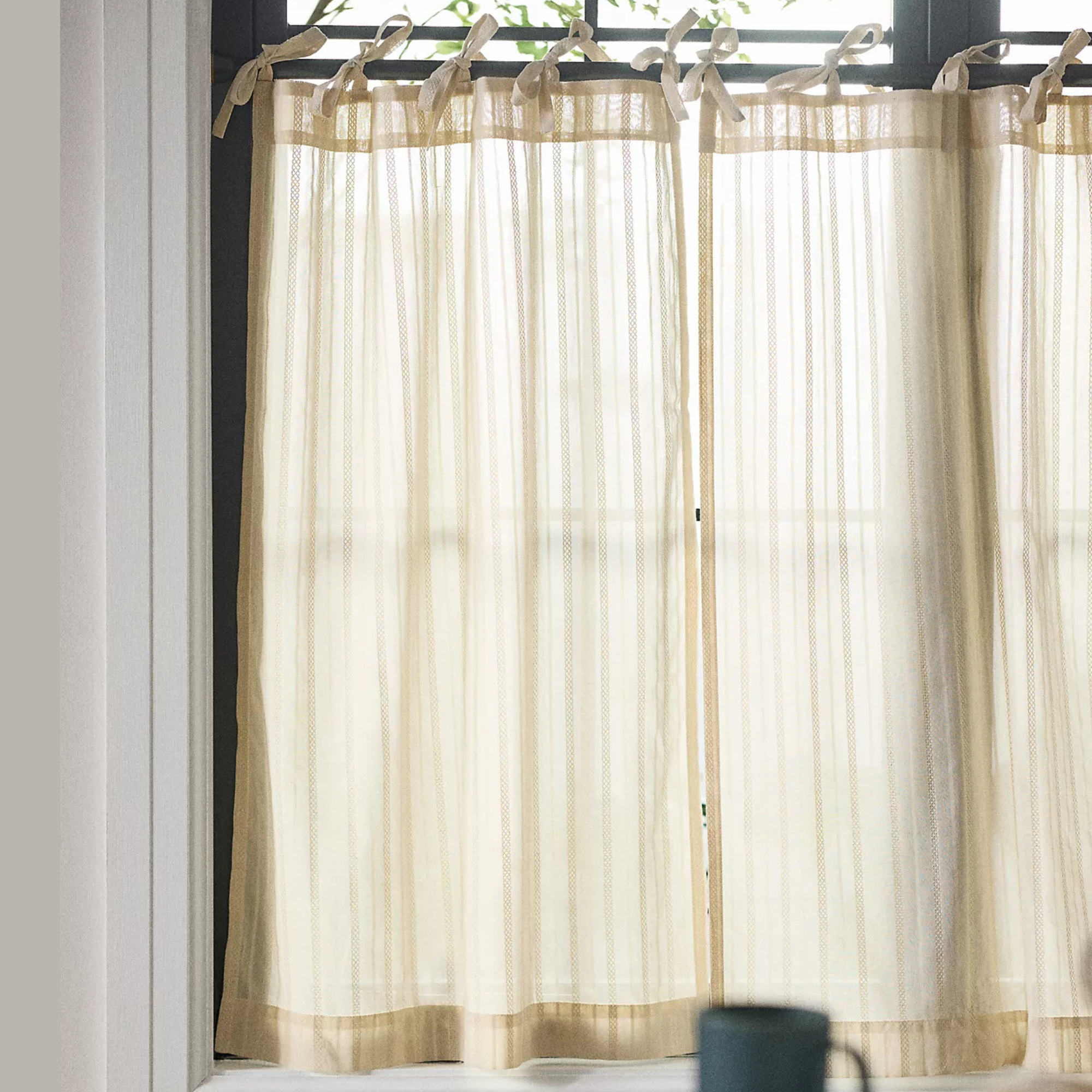 Transparent beige curtains with small bows at the top from Anthropologie
