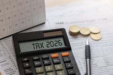 Annual tax planning concept with calculator displaying TAX 2026, stacks of coins, a calendar, and a pen on a wooden desk.